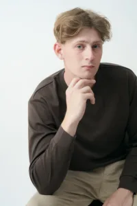 A thoughtful young man in a dark long-sleeve shirt poses for a casual portrait in a Tokyo photography studio, ideal for personal branding and model portfolios.