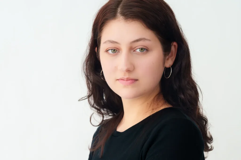 妆容清淡、佩戴圆环耳环的女性职业形象照特写，由 JG 在东京拍摄。