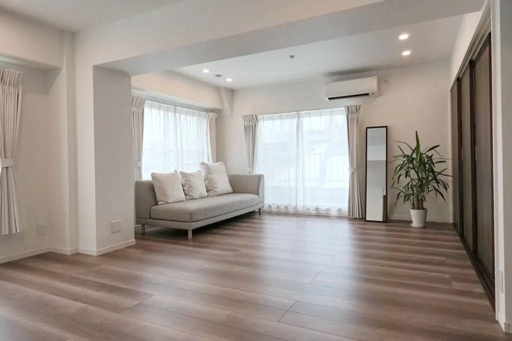 The main room of JG Studio located in Tokyo, Shibuya. An open space featuring a gray sofa and a balcony, with natural light pouring in through large windows.