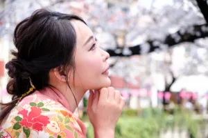 東京で満開の桜の下、花柄のピンクの着物を纏い佇む女性の横顔。