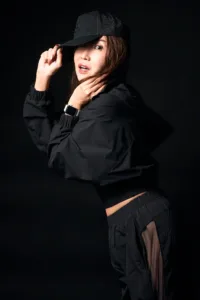 Professional studio portrait of a woman in Tokyo wearing a black Alo Yoga streetwear ensemble, including a mesh cap and windbreaker, captured by JG Brasseur.