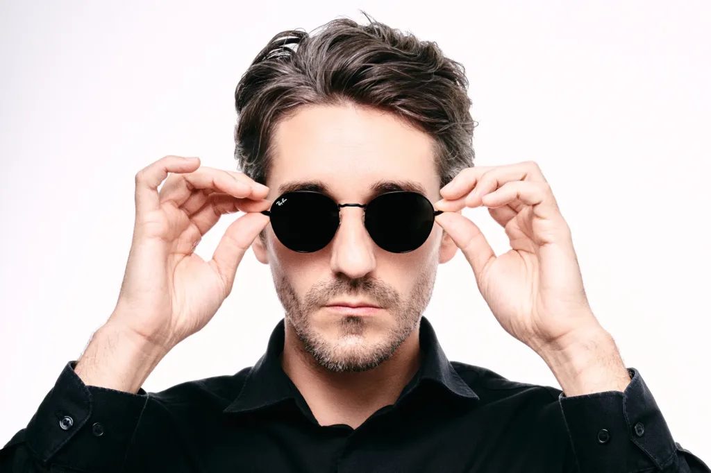 Men's fashion portrait in round black sunglasses against a white studio background, Tokyo.